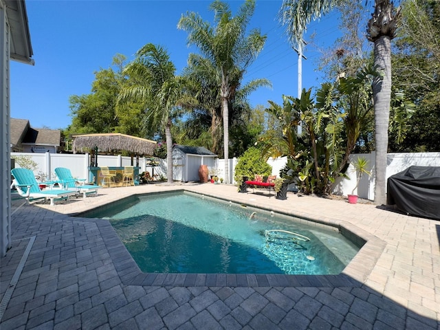 view of pool featuring a patio area, a fenced in pool, a storage unit, and a fenced backyard