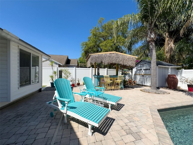 view of patio / terrace with outdoor dining space, an outbuilding, a fenced backyard, and a storage shed