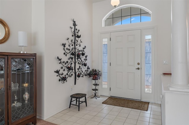 foyer entrance featuring light tile patterned flooring, a healthy amount of sunlight, and baseboards