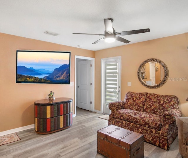 living area with visible vents, ceiling fan, baseboards, and wood finished floors