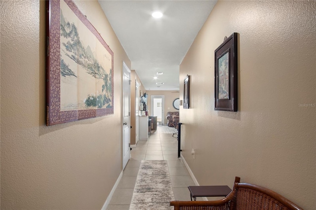 hall featuring baseboards and light tile patterned floors