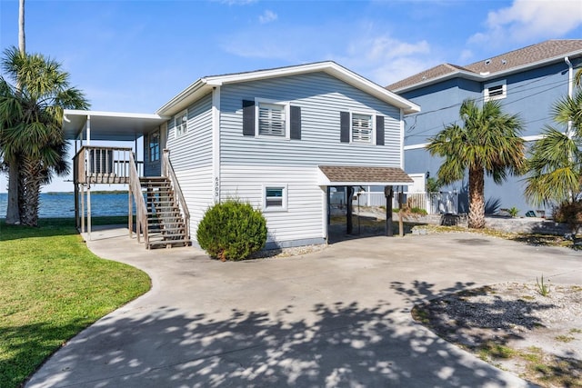 raised beach house with stairs, a front lawn, and driveway