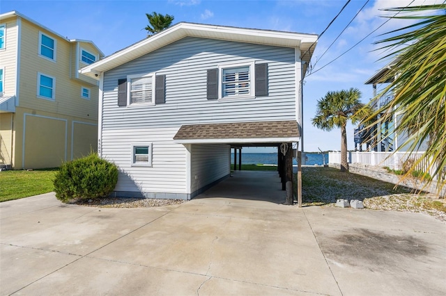 exterior space featuring a carport, driveway, and roof with shingles