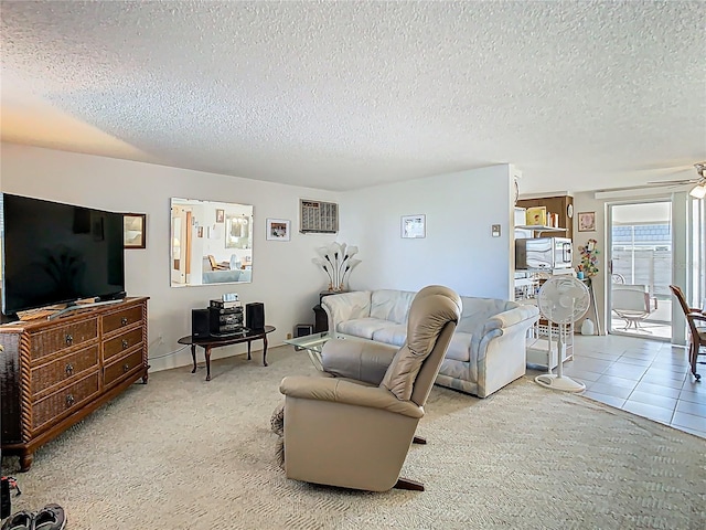 living area featuring carpet flooring, ceiling fan, a textured ceiling, and tile patterned floors