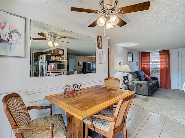 tiled dining space featuring a textured ceiling, carpet floors, and ceiling fan