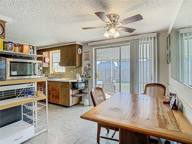 dining area with a textured ceiling, a ceiling fan, and light tile patterned flooring