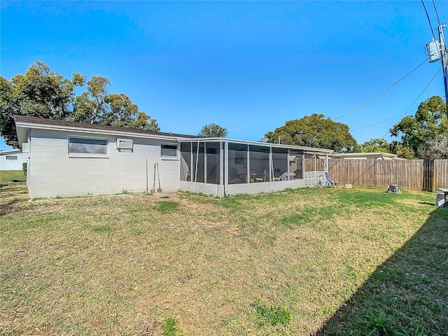 back of property with a sunroom, fence, and a lawn