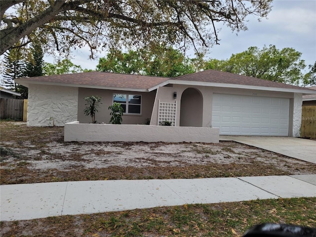 view of front of house with a garage, driveway, fence, and stucco siding