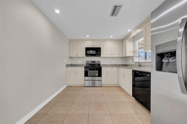 kitchen featuring light tile patterned floors, light stone countertops, visible vents, a sink, and black appliances