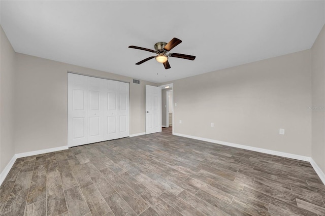 unfurnished bedroom with a closet, visible vents, baseboards, and wood finished floors