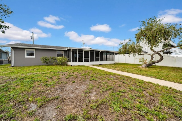 rear view of house with a yard, a fenced backyard, and a sunroom