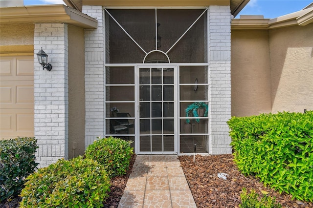 entrance to property with a garage and brick siding