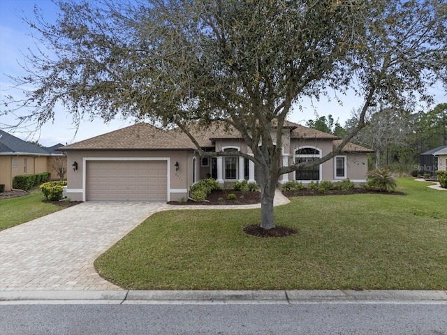 ranch-style house featuring a front lawn, decorative driveway, an attached garage, and stucco siding