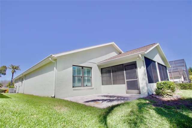 back of house with a patio area, a lawn, a sunroom, and stucco siding