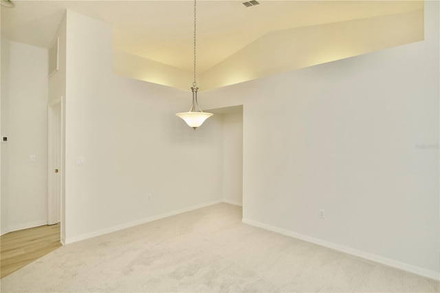 spare room with baseboards, light carpet, visible vents, and vaulted ceiling