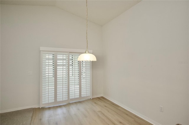 spare room with light wood-type flooring, baseboards, and high vaulted ceiling