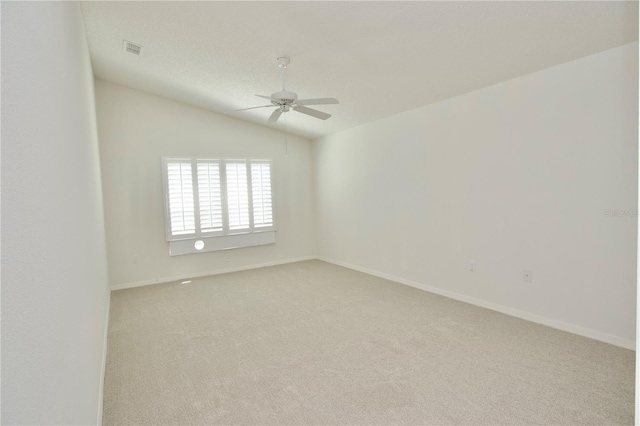 empty room with baseboards, visible vents, lofted ceiling, ceiling fan, and light colored carpet