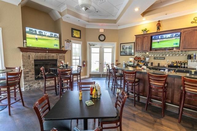 dining area with a dry bar, a raised ceiling, crown molding, and a fireplace