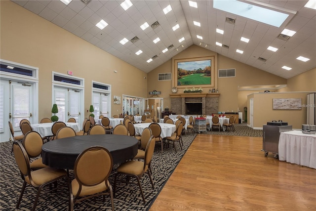 dining area featuring light wood finished floors, visible vents, and high vaulted ceiling