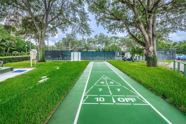 surrounding community featuring a tennis court, shuffleboard, a yard, and fence