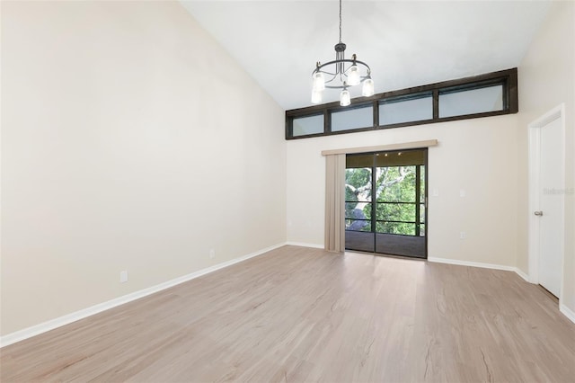 spare room with light wood-type flooring, high vaulted ceiling, baseboards, and a notable chandelier