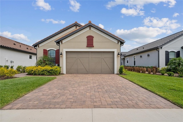 view of front of home with a front lawn, decorative driveway, an attached garage, and stucco siding