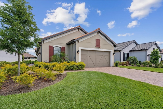 mediterranean / spanish house with a front lawn, decorative driveway, an attached garage, and stucco siding