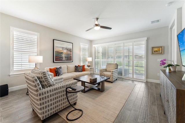 living room featuring a wealth of natural light, baseboards, visible vents, and wood finished floors