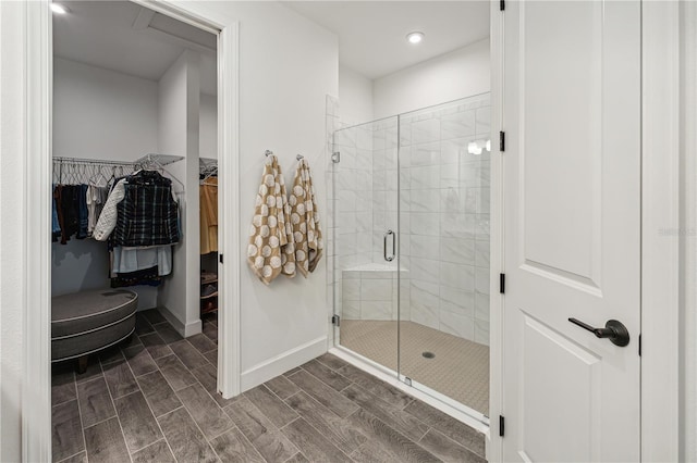 full bathroom featuring wood tiled floor, a shower stall, baseboards, and a spacious closet