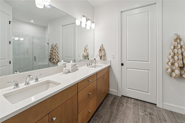 bathroom featuring double vanity, wood finish floors, a sink, and a stall shower