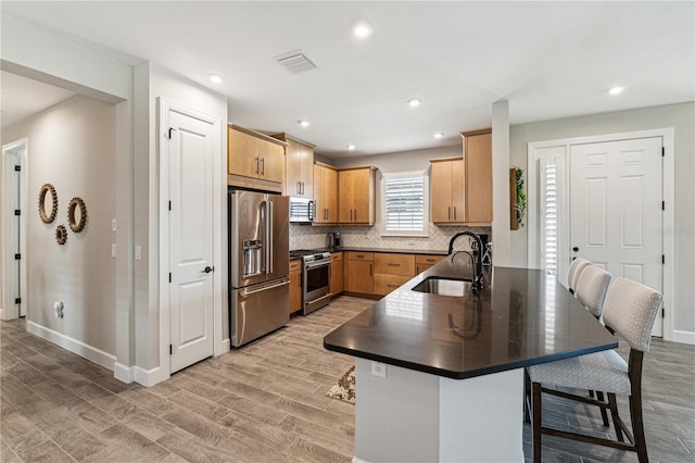 kitchen with visible vents, premium appliances, dark countertops, a peninsula, and a sink