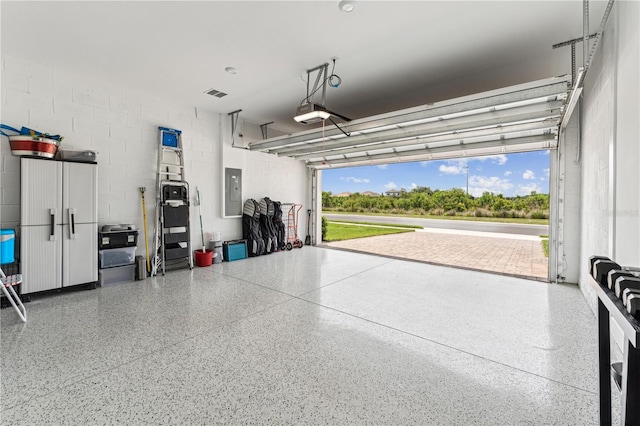 garage with visible vents, concrete block wall, electric panel, and a garage door opener