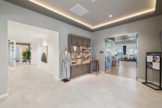 corridor featuring recessed lighting, a raised ceiling, visible vents, and baseboards