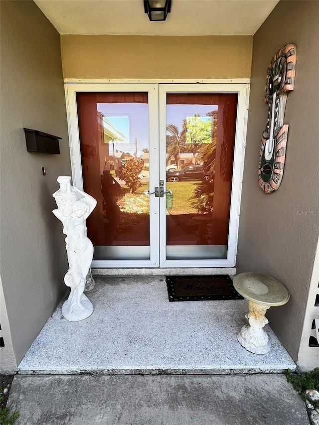 property entrance with stucco siding and french doors