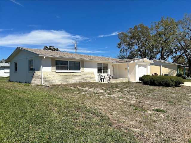 single story home featuring a front yard, stone siding, an attached garage, and stucco siding