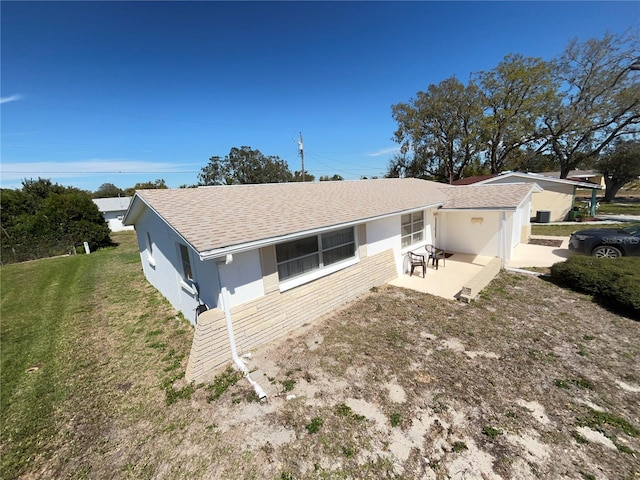 view of front of property with brick siding, roof with shingles, stucco siding, a front lawn, and a patio area