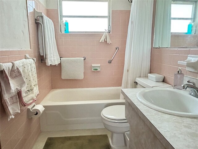 bathroom with toilet, vanity, tile walls, and a healthy amount of sunlight