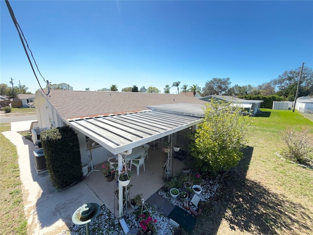 view of side of home with roof with shingles, a yard, stucco siding, a patio area, and metal roof