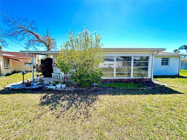 rear view of property featuring stucco siding and a yard