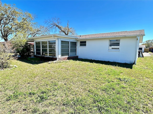 back of property with a lawn and stucco siding