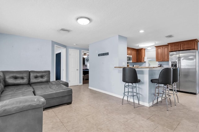 kitchen with open floor plan, a breakfast bar area, visible vents, and stainless steel appliances