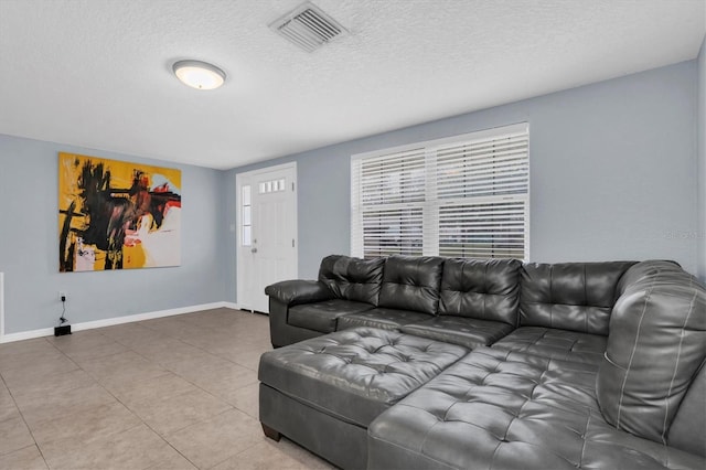 tiled living room featuring visible vents, a textured ceiling, and baseboards