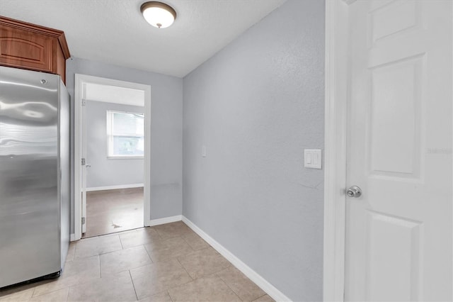 interior space with light tile patterned floors, baseboards, and a textured ceiling