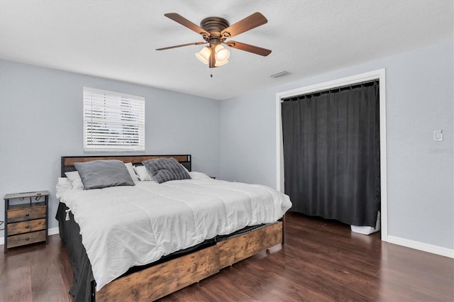 bedroom featuring a ceiling fan, wood finished floors, visible vents, and baseboards