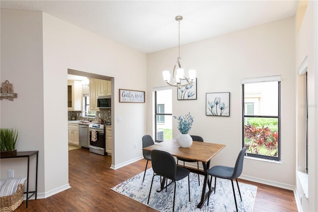 dining area featuring dark wood-style floors, baseboards, and a chandelier