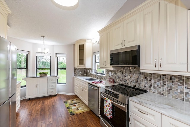 kitchen featuring dark wood-style flooring, a sink, appliances with stainless steel finishes, tasteful backsplash, and glass insert cabinets