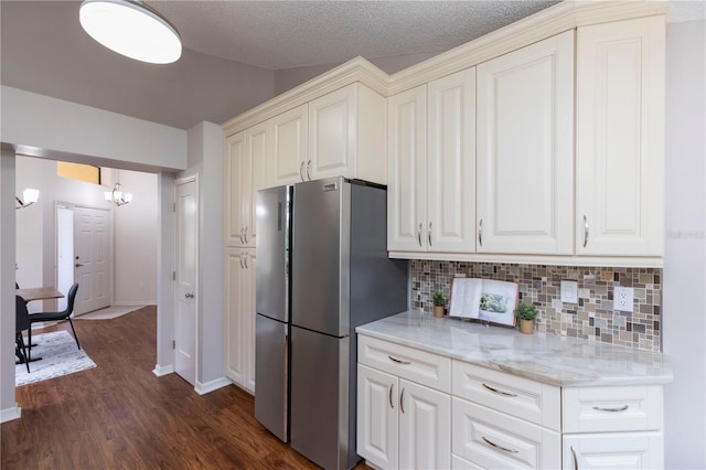 kitchen featuring tasteful backsplash, white cabinets, dark wood-style floors, freestanding refrigerator, and light stone countertops