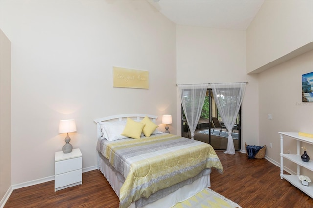 bedroom featuring a high ceiling, baseboards, and wood finished floors