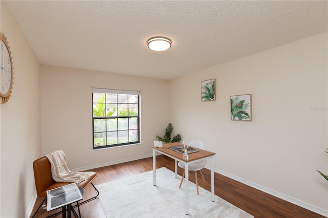 office area with a textured ceiling, wood finished floors, and baseboards