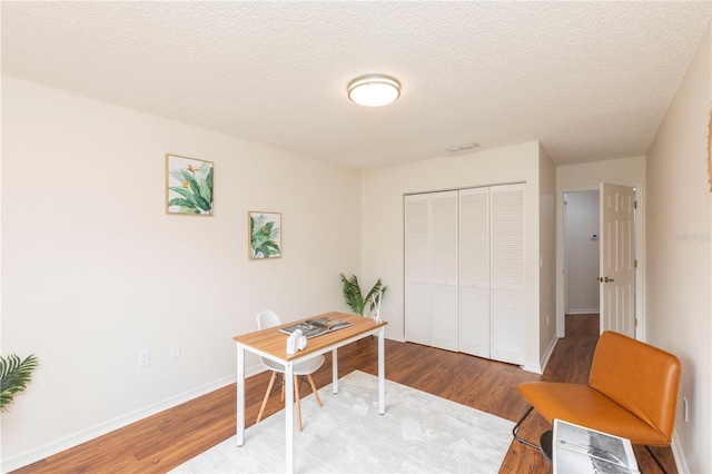 office featuring visible vents, a textured ceiling, baseboards, and wood finished floors